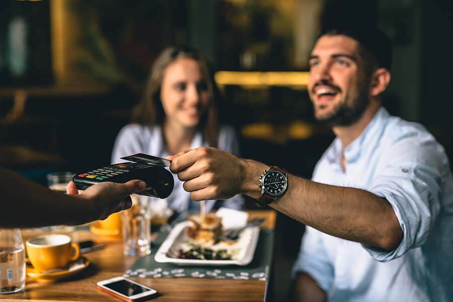 A man paying at a restaurant using his credit builder credit card.